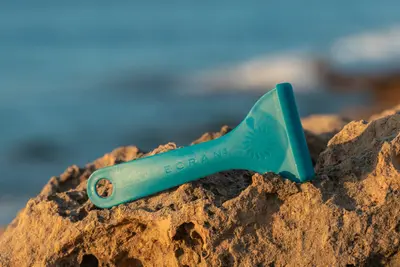 Uno de los modelos de espátula Meduclean con pantalla de color azul marino sobre una roca.