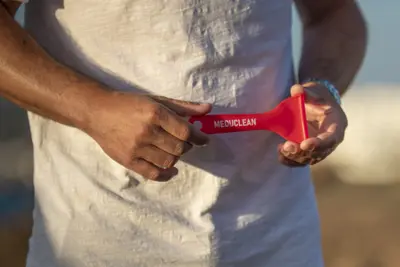 Persona que sostiene con ambas manos la espátula Meduclean de color rojo.